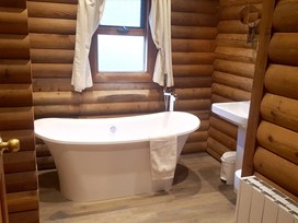 freestanding white bath in a log-clad cabin