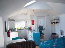 Inside view of Stable Studio showing small kitchen, part of bed and seating area.